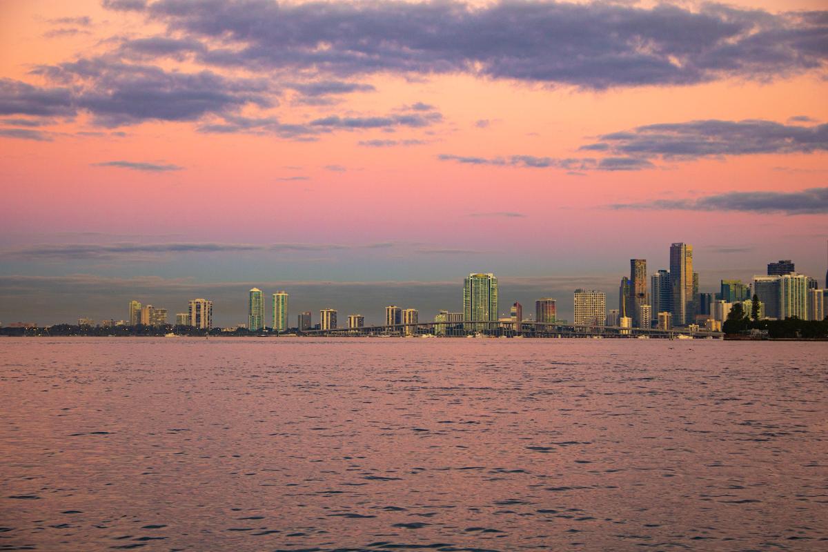 Florida waterfront cityscape at sunset with pink and purple sky, illustrating the state's year-round warm climate and coastal environment for detox recovery