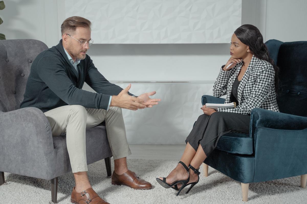 Therapist and client seated facing each other in a counseling session, using motivational interviewing techniques to explore goals, build motivation, and support behavior change.