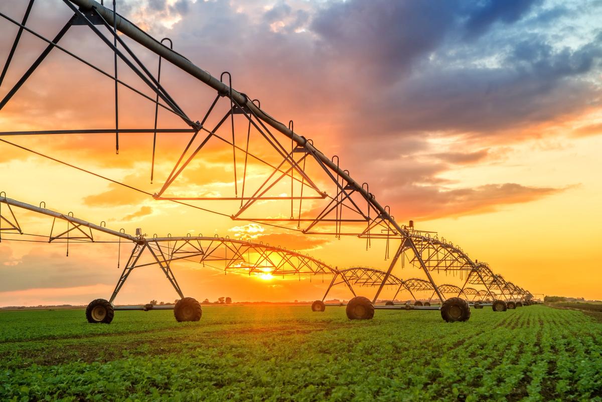 Large agricultural irrigation systems stretching across a rural field at sunset, symbolizing isolation, distance, and the challenges of accessing addiction recovery resources in rural communities.