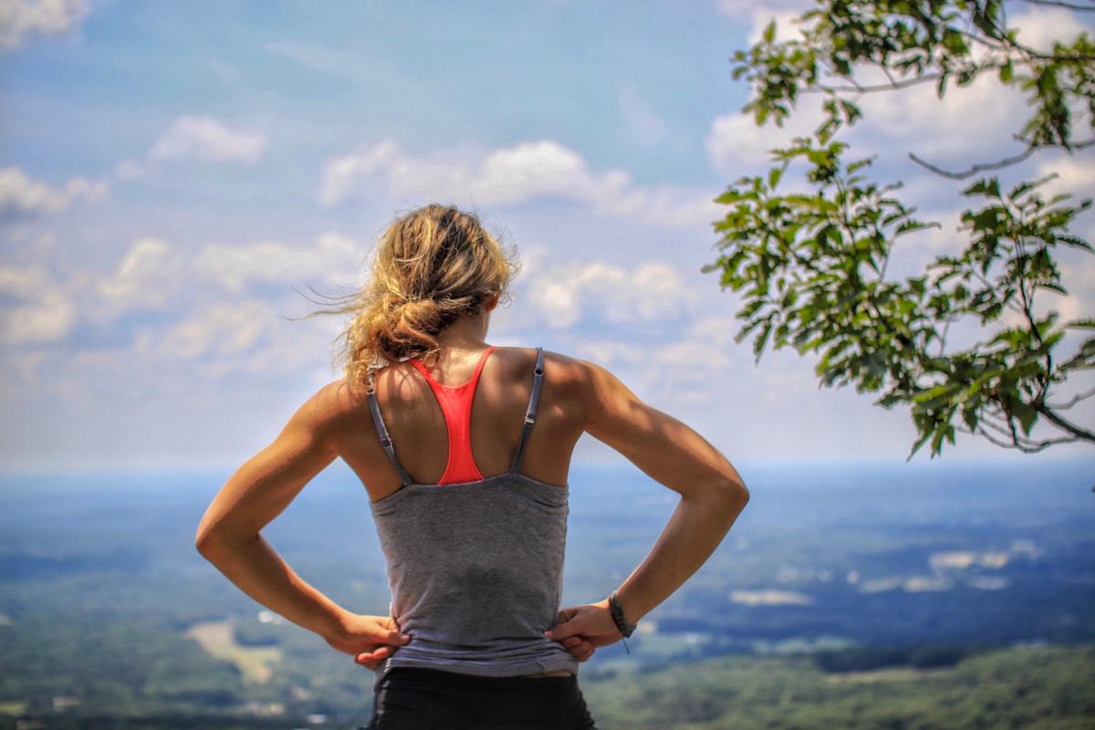 An athlete standing with hands on hips overlooking a wide natural landscape, symbolizing strength, privacy, and personal reflection in the context of rehab confidentiality and protected recovery journeys.