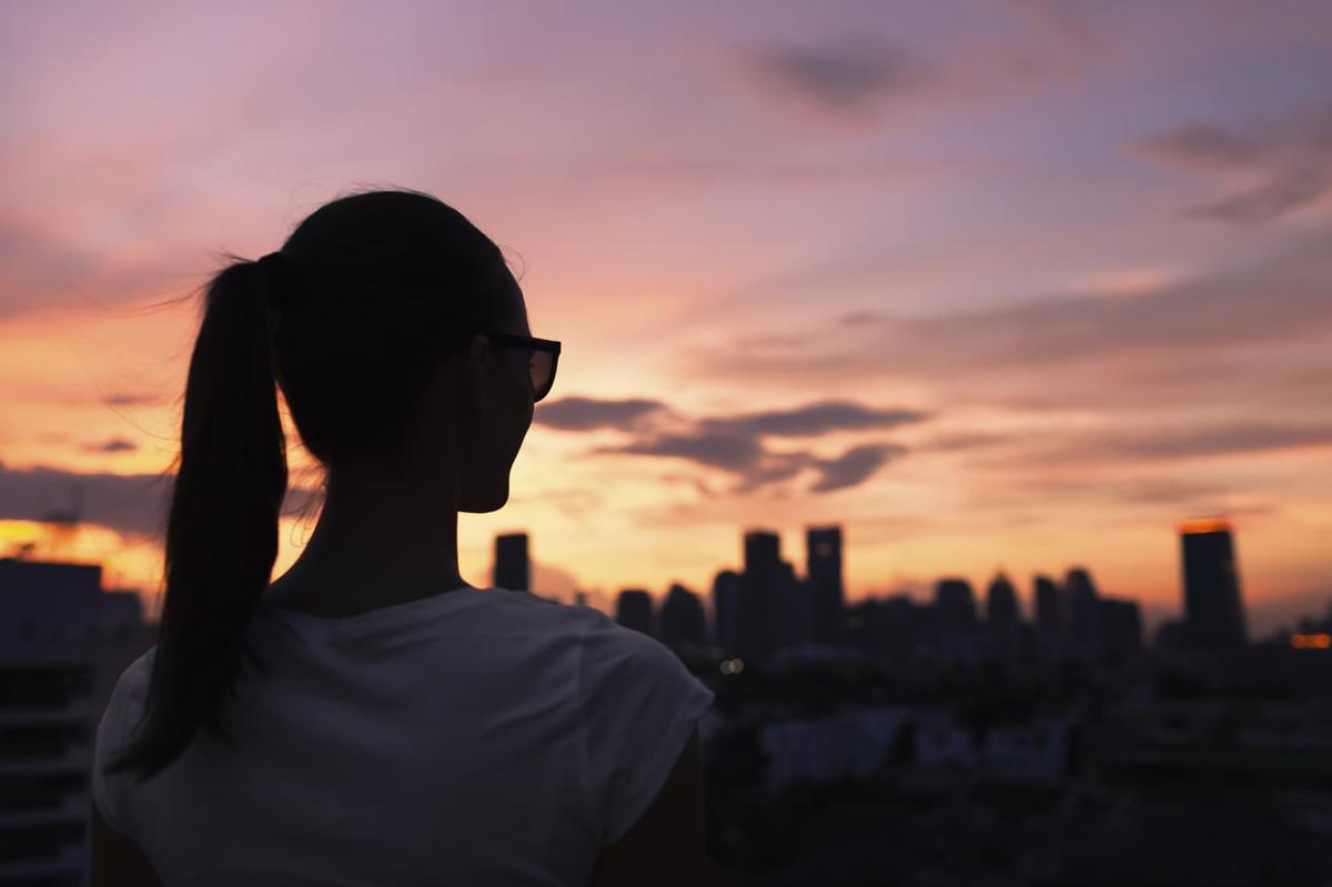 Silhouette of a person in thoughtful moment during sunset, illustrating recovery and personal transformation
