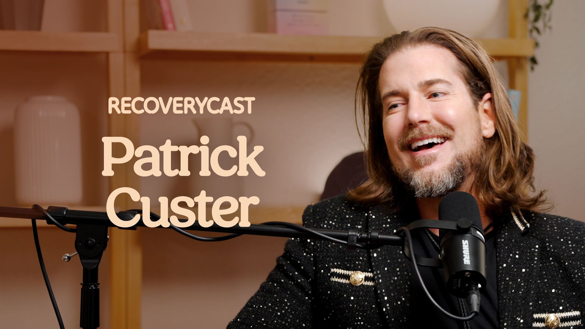 Recoverycast podcast guest Patrick Custer smiling during an interview, discussing addiction recovery, sobriety, and mental health with a microphone in a studio setting