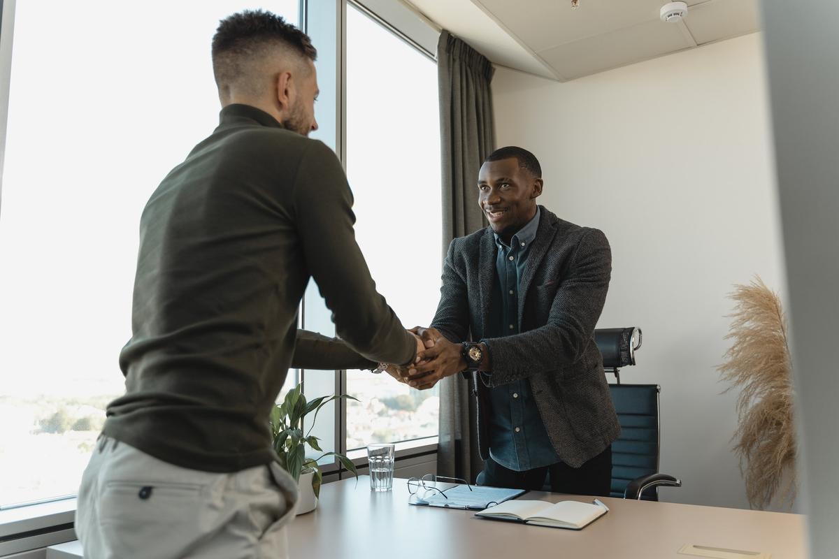 Two men shaking hands and smiling after a successful job interview.