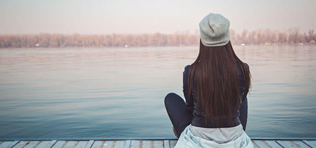 Women sitting alone at a lake contemplating mental health struggles