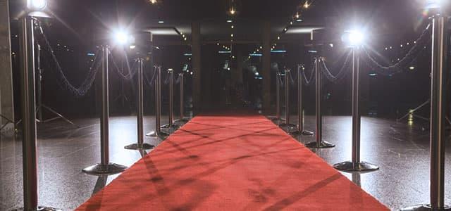 Red carpet with velvet rope barriers and bright lights, symbolizing celebrity culture and the public pressure faced by famous people struggling with heroin addiction