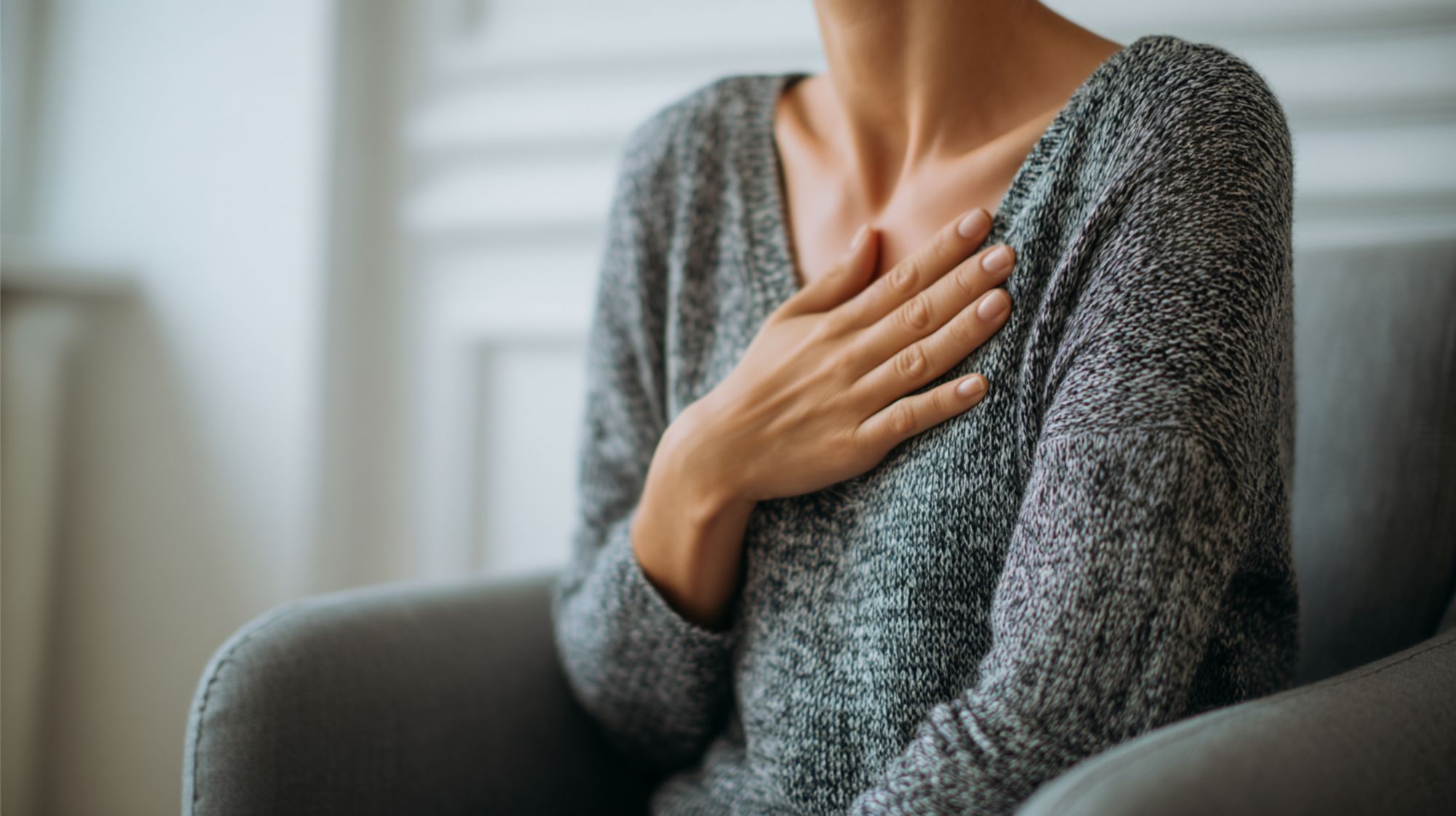 Person with hand on chest experiencing difficulty breathing, illustrating the dangerous respiratory depression caused by mixing alcohol and heroin