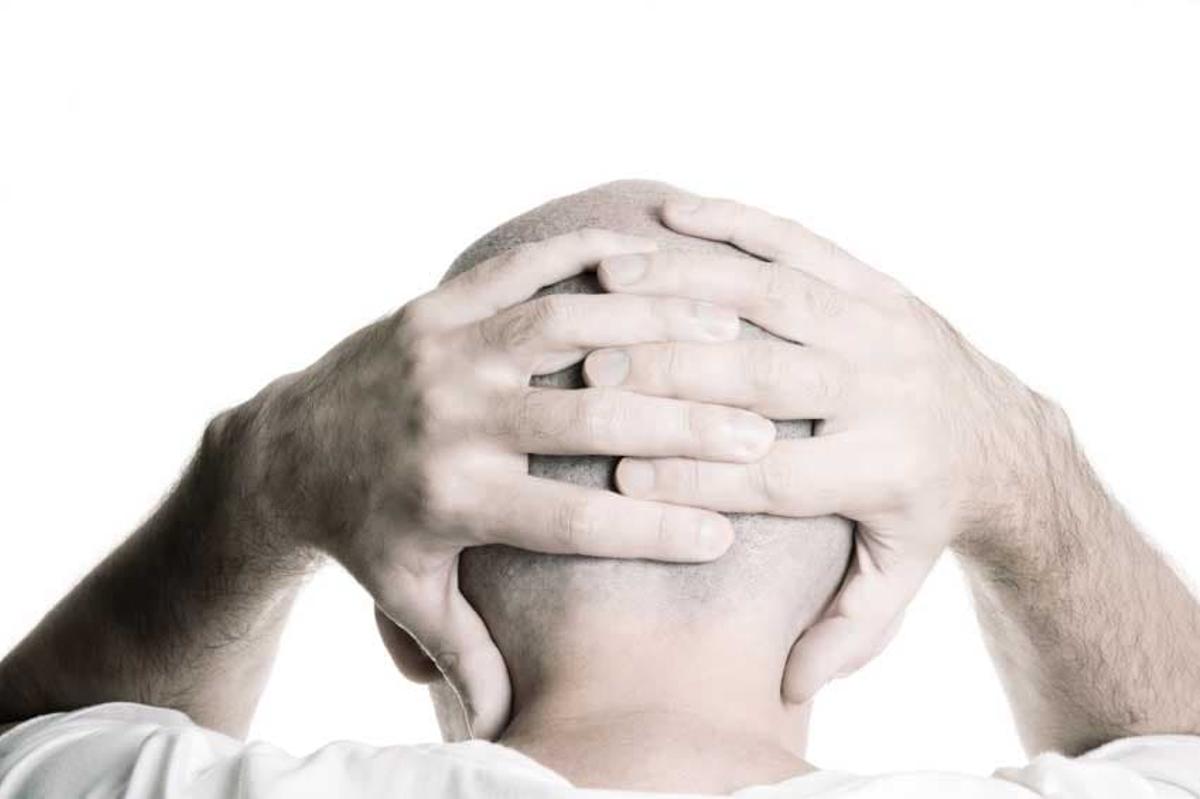 A man holding the back of his head, stressed, symbolizing chaos and unrest.