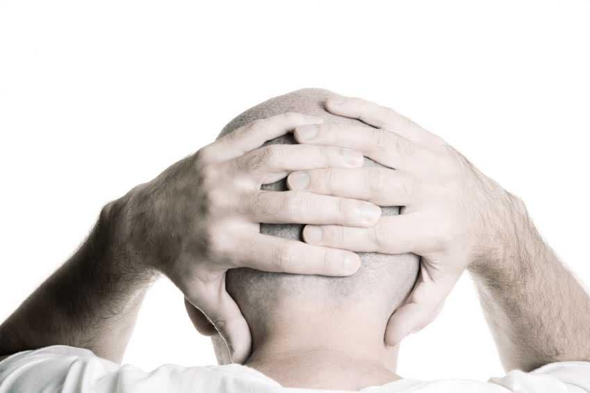 A man holding the back of his head, stressed, symbolizing chaos and unrest.