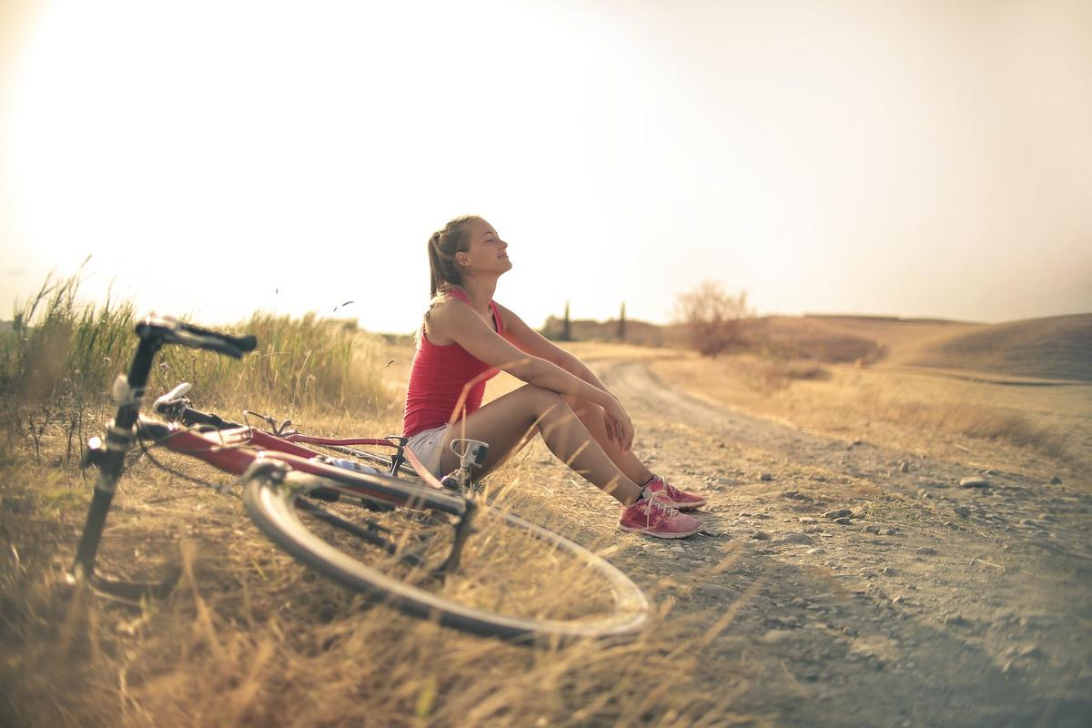Woman taking peaceful break during bike ride on country road, showing healthy smoke-free lifestyle and outdoor activity