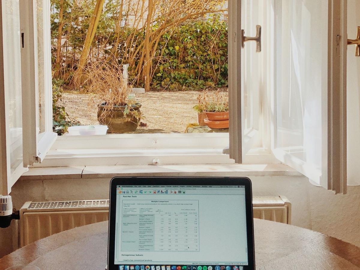 Laptop displaying spreadsheet on desk beside bathtub with garden view, representing work flexibility in executive rehab facilities