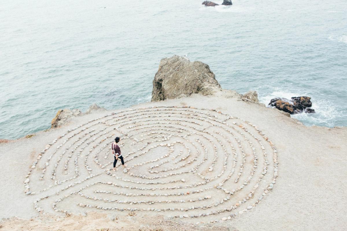 Person walking a spiral labyrinth by the ocean, symbolizing recovery journey and finding path to healing in rehab