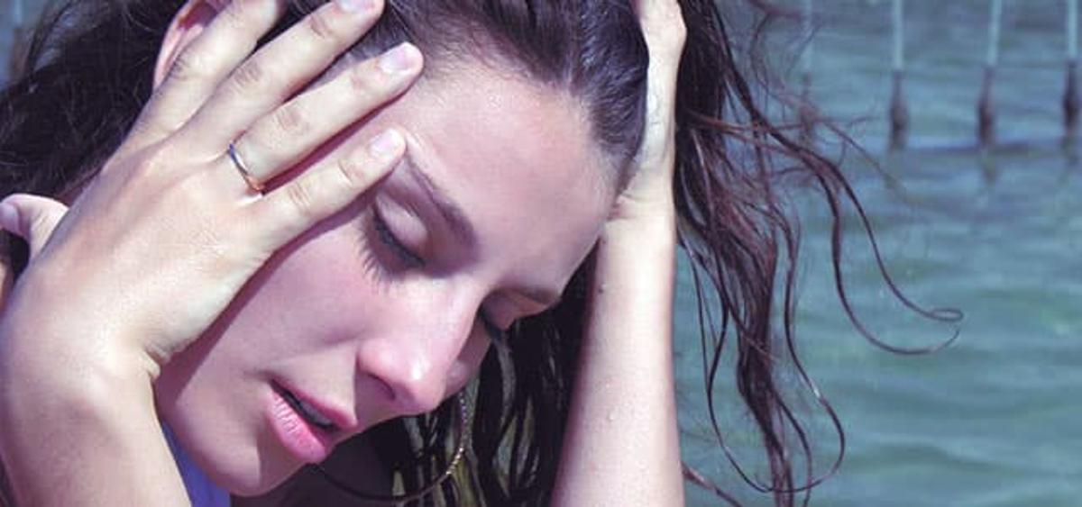 Person with hand to forehead and eyes closed, appearing drowsy and disoriented, illustrating common symptoms of tranquilizer overdose such as sedation and impaired consciousness