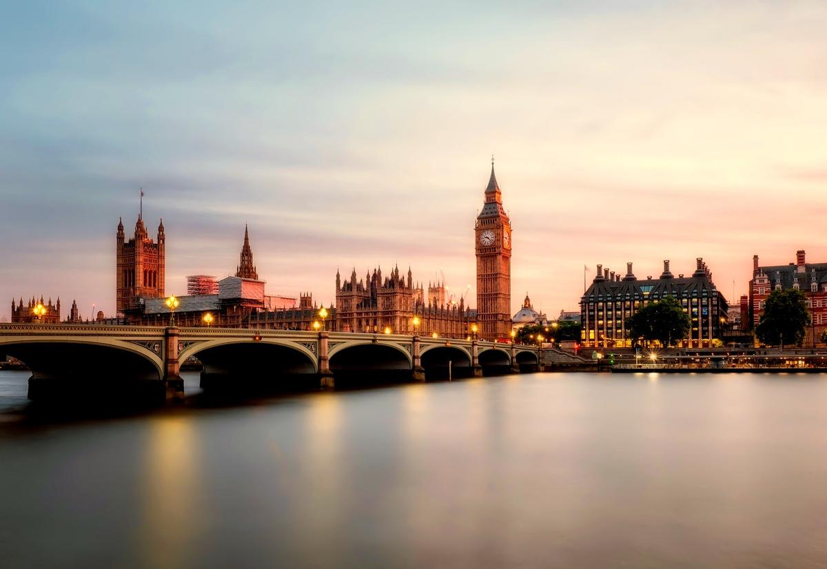 Long exposure sunset view of the Palace of Westminster, Big Ben, and Westminster Bridge over the River Thames in London.