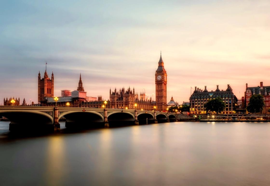 Long exposure sunset view of the Palace of Westminster, Big Ben, and Westminster Bridge over the River Thames in London.