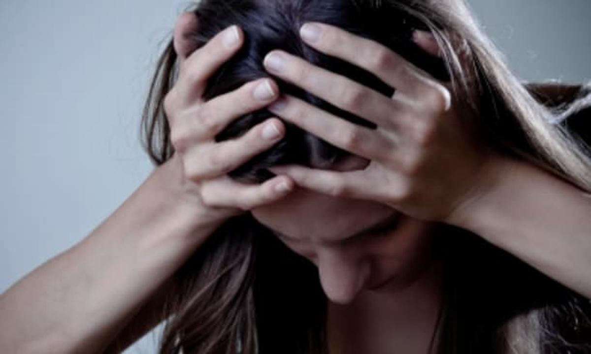 Woman holding her head in her hands and looking downward, showing signs of stress or emotional distress.