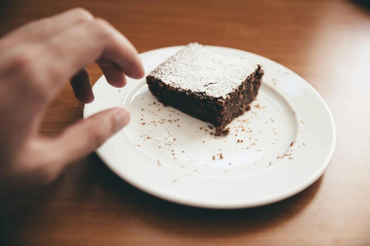 Hand reaching for a brownie on a plate, representing managing drug cravings and resisting temptation during addiction recovery.
