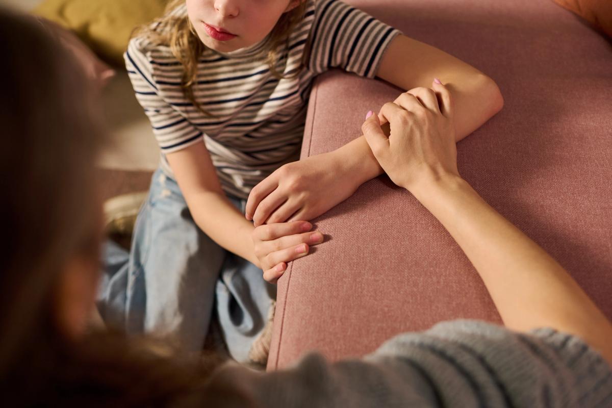 A young girl receiving comforting support from an adult woman during a difficult conversation, expressing care and trust. 