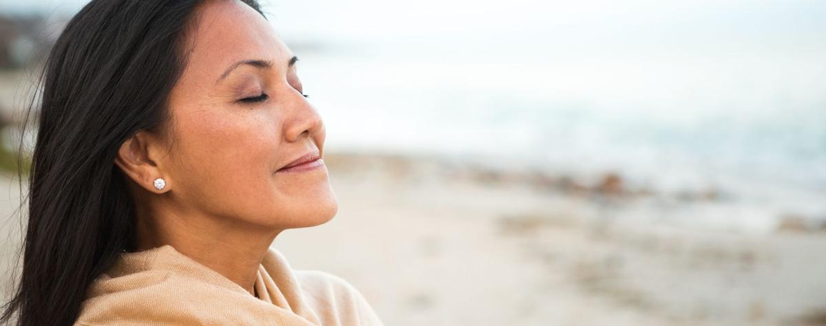 Woman practicing calming breathing exercise outdoors for panic attack relief