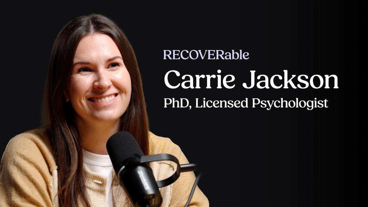 Professional headshot of Carrie Jackson, a smiling woman with long brown hair, wearing a beige cardigan, speaking into a large podcast microphone against a black background.