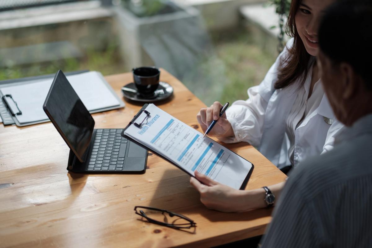 Healthcare professional reviewing insurance coverage documents with patient at consultation table