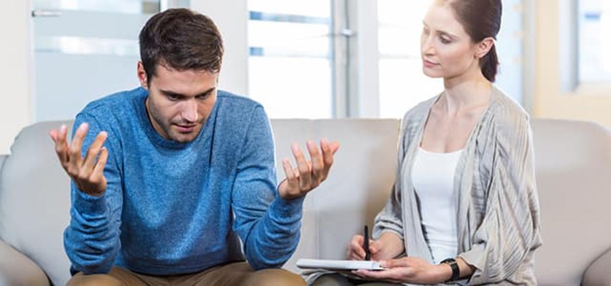 Man in distress during behavioral health therapy session with counselor at dual diagnosis treatment center