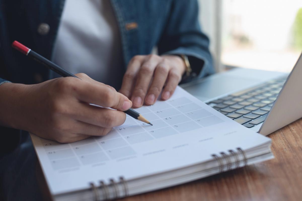 Person marking dates on a calendar beside a laptop, symbolizing planning, commitment, and practical steps for how to quit vaping and build healthier habits.