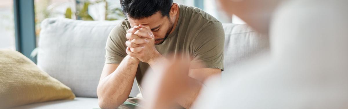 Person with hands clasped near face appearing distressed, showing the emotional impact of complex trauma