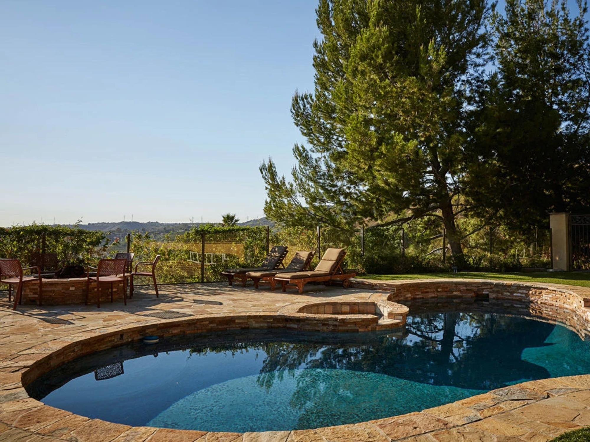 Luxury rehab center pool area with stone decking and lounge chairs surrounded by vineyards and rolling hills