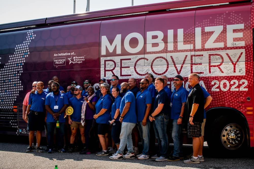 Mobilize Recovery tour bus with recovery advocates and community members gathered for addiction recovery awareness event and outreach campaign.