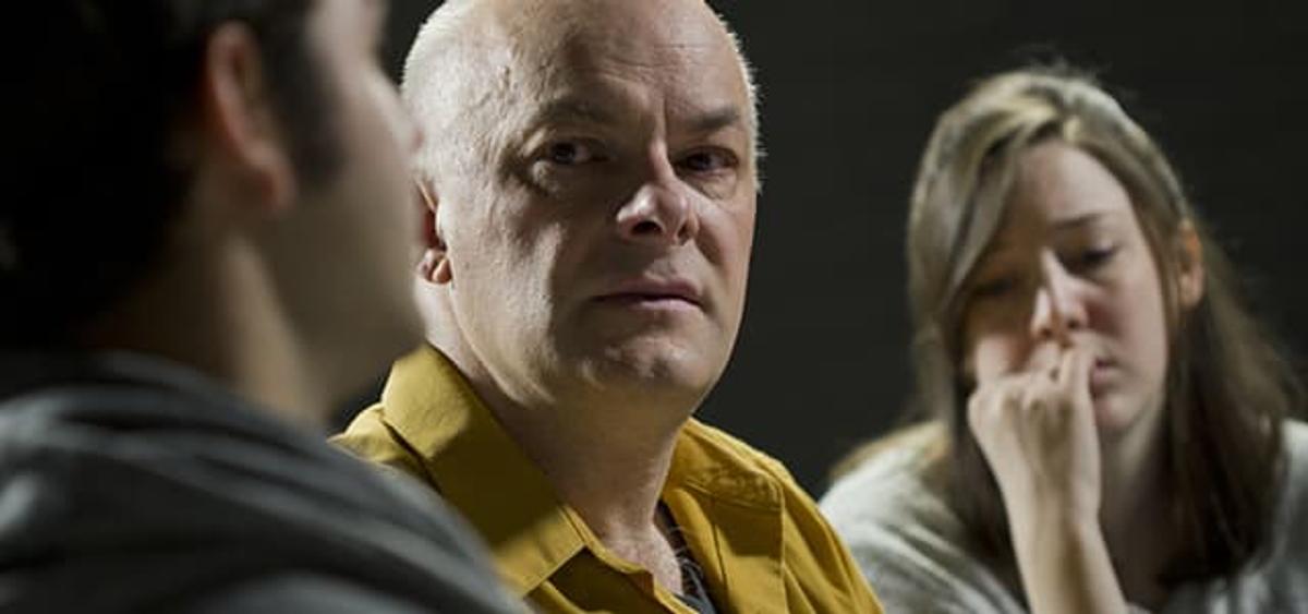 Person sharing at 12-step support group meeting with others listening, illustrating the supportive environment of addiction recovery meetings