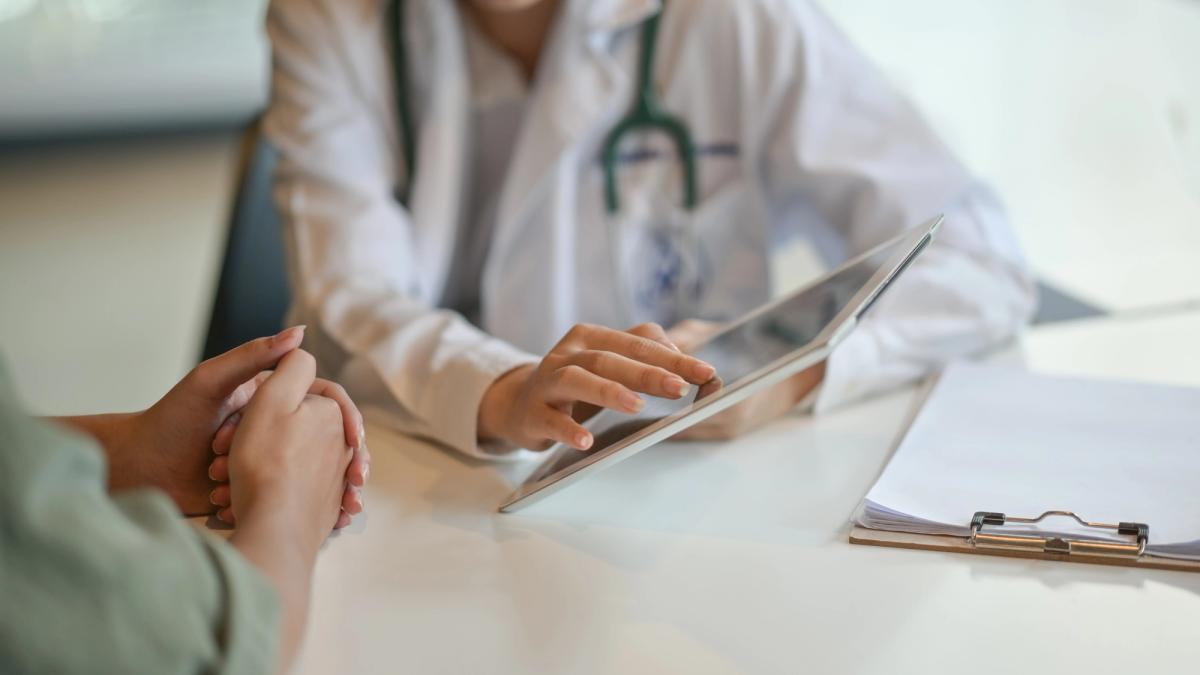 Doctor reviewing information on a tablet while consulting with a patient, representing medical support and treatment during substance withdrawal.