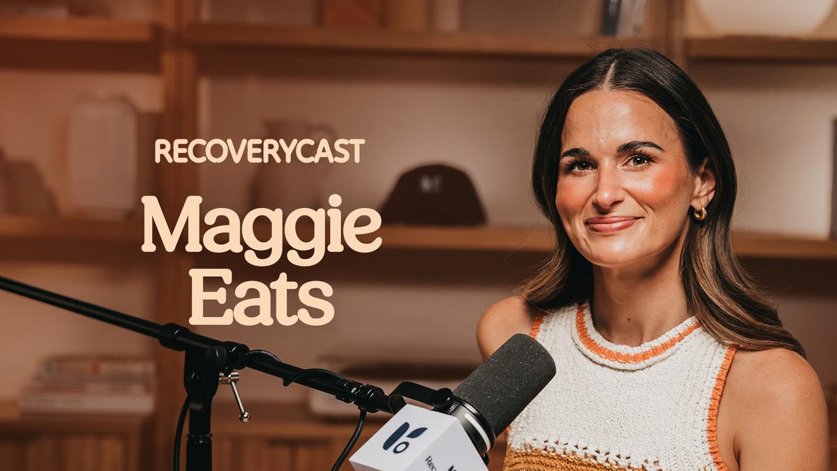 Influencer and recovery advocate Maggie Eats sitting in front of a podcast microphone. Maggie smiles at the camera while seated in a warm, softly lit studio with wooden shelves in the background. Large text on the left reads “Recoverycast” and “Maggie Eats.”