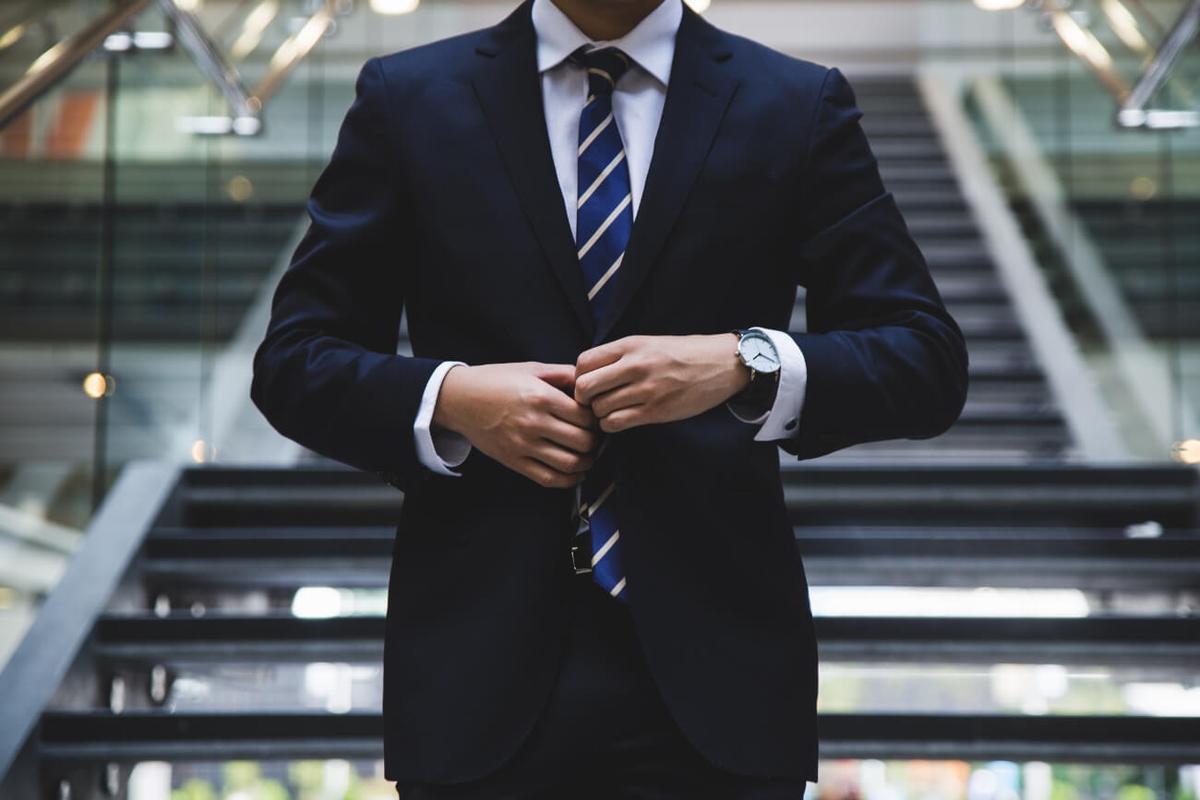 Professional attorney in a dark suit adjusting his jacket in an office building, representing the hidden reality of addiction among high-achieving professionals and lawyers.