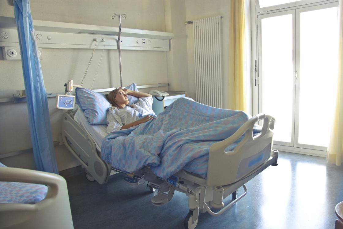 Person lying in hospital bed receiving medical care for alcohol poisoning symptoms, emphasizing need for professional treatment