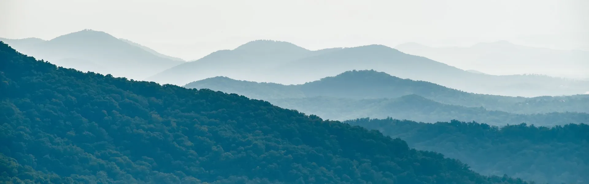 Layers of misty blue mountains fading into the distance, symbolizing peace, resilience, and the journey of recovery.