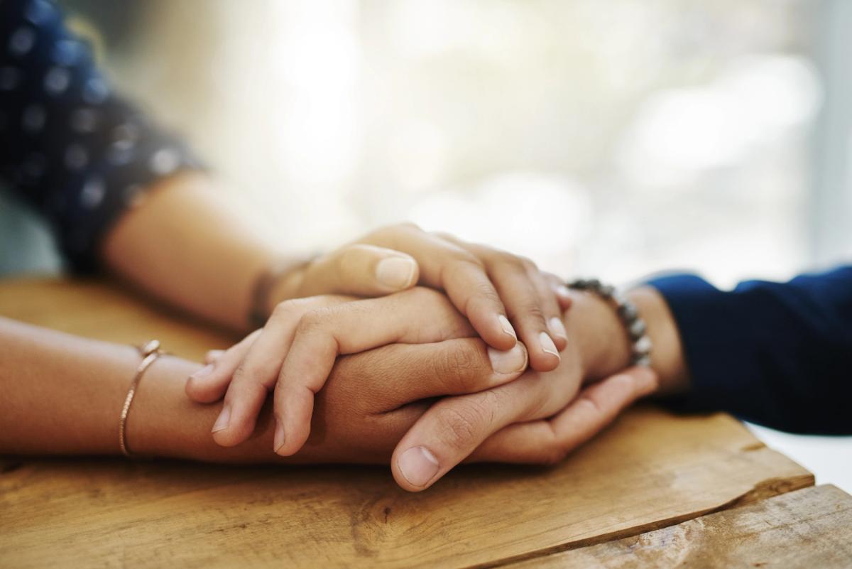 Two people holding hands in support, symbolizing compassion, encouragement, and connection in addiction recovery.