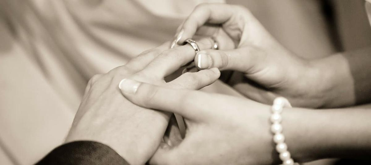 Close-up of hands exchanging a wedding ring, symbolizing commitment, love, and relationship milestones during marriage or life transitions.