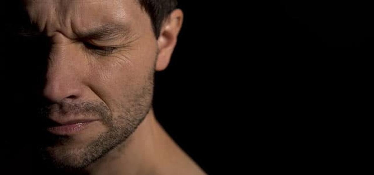 Person with eyes closed appearing emotionally distressed, representing the mental health struggles of PTSD and trauma-related stress