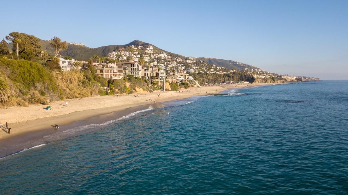 Scenic Orange County beach with turquoise water and hillside homes, showcasing the coastal setting where rehabs offer outdoor therapy and recovery programs