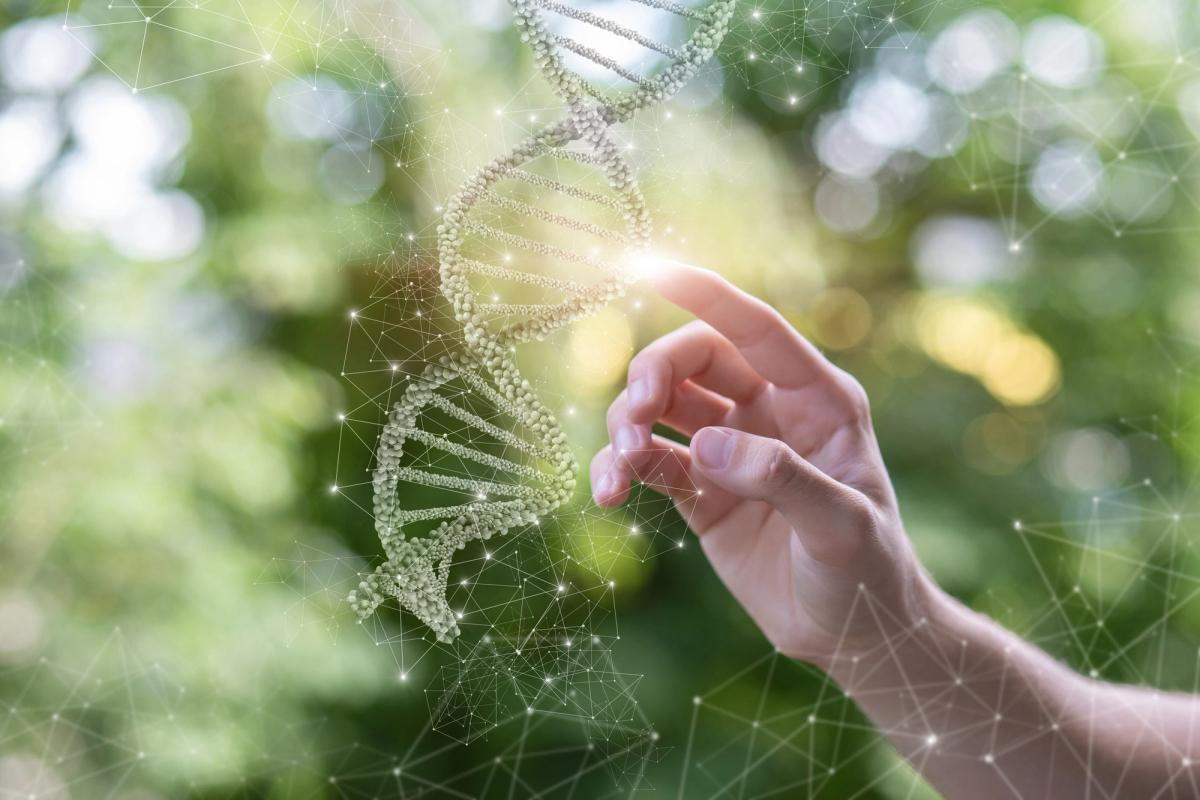 A hand reaching toward a glowing DNA double helix, illustrating genetic factors and the idea of being predisposed to addiction through biology and heredity.