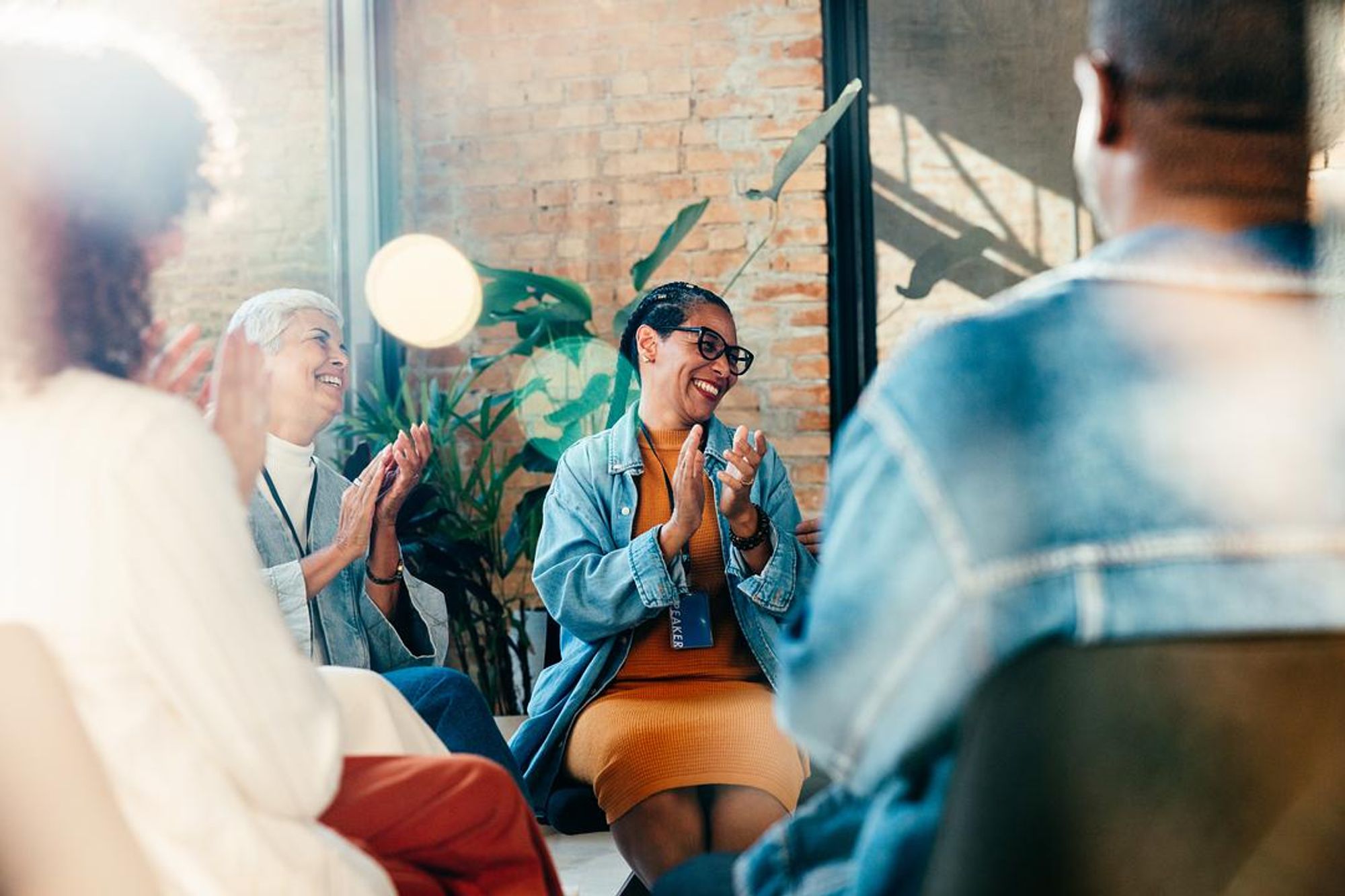Members of a substance use recovery support group applauding during a positive moment in a group therapy session.