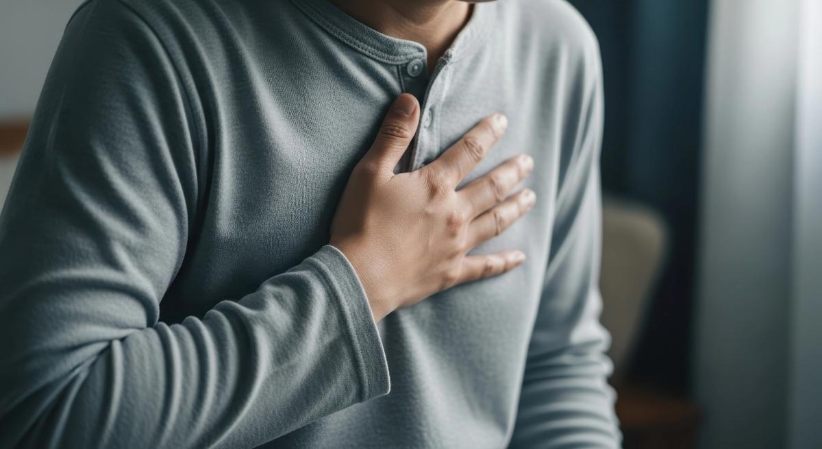 Person with hand on chest experiencing respiratory or cardiac distress, illustrating the dangerous breathing and heart effects of mixing alcohol and opioids