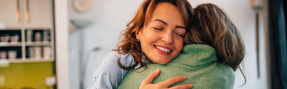 Smiling woman with eyes closed embracing a loved one in a warm hug, symbolizing the gift of recovery and the joy of healing relationships.