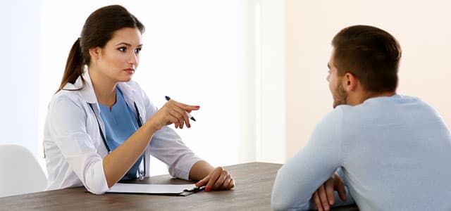 A patient sitting at a table with their doctor.