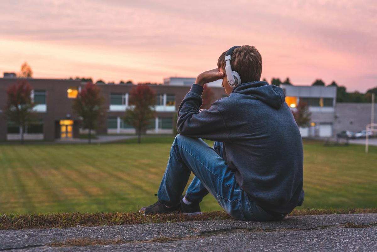 Young person sitting alone at dusk wearing headphones, depicting isolation and emotional withdrawal common in marijuana addiction symptoms