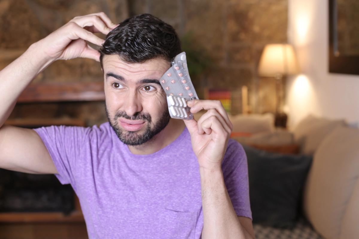Man holding blister packs of prescription pills appearing confused, illustrating the dangers of mixing benzodiazepines and opioids