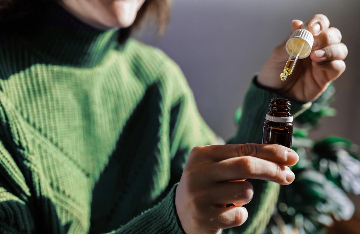 Person holding a dropper bottle of CBD oil, representing the use of CBD in addiction recovery and healing.